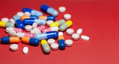 Kırmızı arka planda yığınla hap, tablet, kapsül. Uyuşturucu öncülü