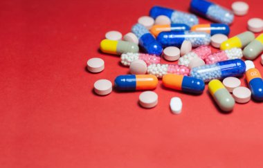 Kırmızı arka planda yığınla hap, tablet, kapsül. Uyuşturucu öncülü