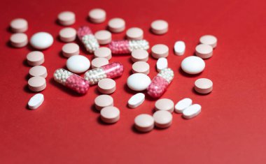 Kırmızı arka planda yığınla hap, tablet, kapsül. Uyuşturucu öncülü