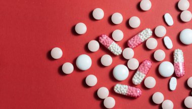 Kırmızı arka planda yığınla hap, tablet, kapsül. Uyuşturucu öncülü