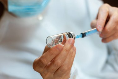 Doktor beyaz ameliyat elbisesi ve mavi maske takıyor.