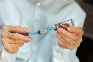 Doktor beyaz ameliyat elbisesi ve mavi maske takıyor.