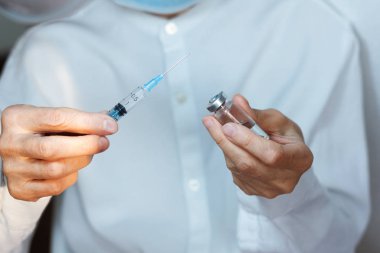 Doktor beyaz ameliyat elbisesi ve mavi maske takıyor.