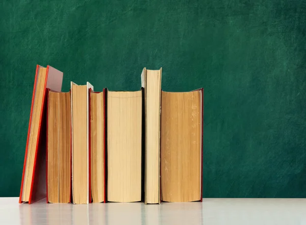 Back to school, pile of books with empty green school board back — Stock Photo, Image