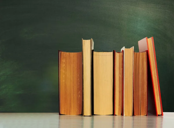 Back to school, pile of books with empty green school board back — Stock Photo, Image