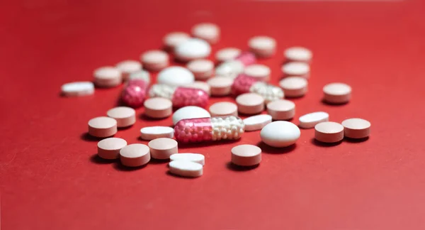 Un mucchio di pillole, compresse, capsule su sfondo rosso. Prescrizioni di farmaci — Foto Stock