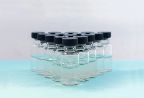 Medicamentos en viales, listos para la inyección de vacunas sobre fondo azul —  Fotos de Stock