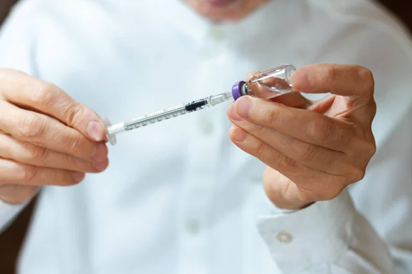 Médico en una bata quirúrgica blanca y máscara azul sostiene en las manos un m — Foto de Stock