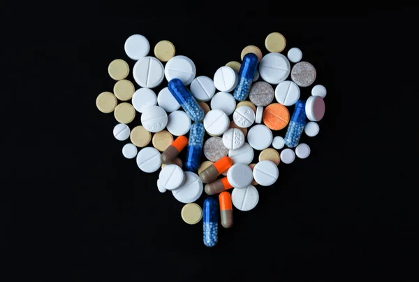黒を背景にハート タブレット カプセルの形をしたカラフルな錠剤のヒープ 治療薬のための薬の処方健康管理の概念 コピースパックとトップビュー — ストック写真