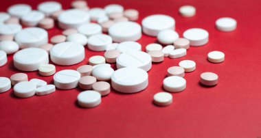 Kırmızı arka planda beyaz haplar, haplar, kapsüller. Fotokopi alanı ile tedavi tedavisi için ilaç reçetesi