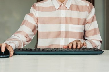 El feneri kullanan ve beyaz masadaki klavye bilgisayarında yazan kadının yakın çekimi, iş konsepti