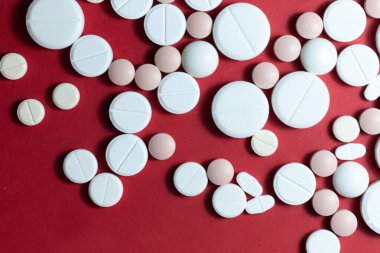 Kırmızı arka planda beyaz haplar, haplar, kapsüller. Fotokopi alanı ile tedavi tedavisi için ilaç reçetesi