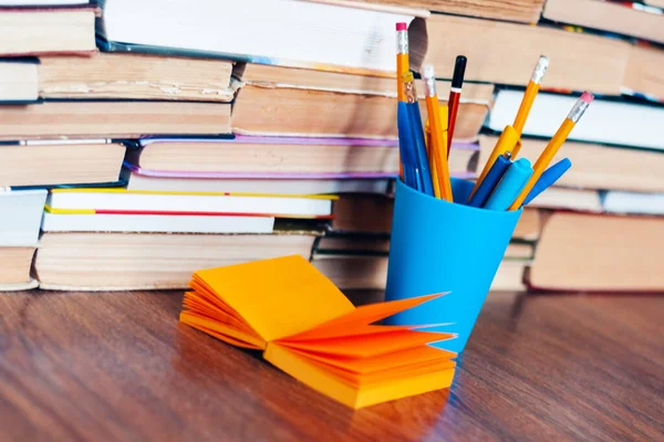 Pencils in holder, note paper and stack of books, school background for education learning concept