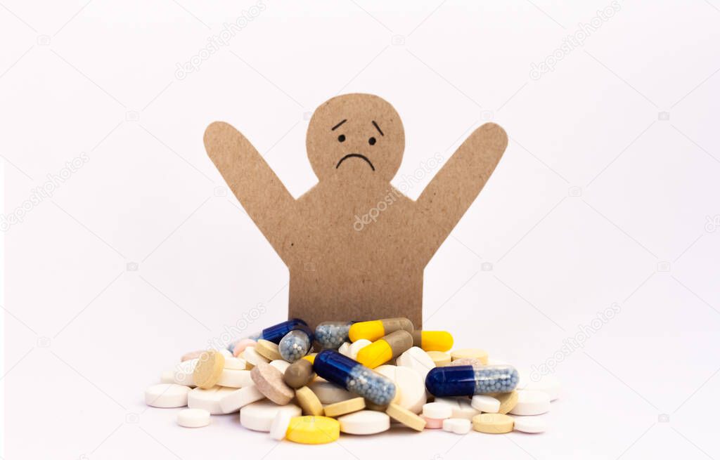 Heap of colorful pills and a figure of a cardboard man, tablets and capsules on white background. Drug prescription for treatment medication health care concept wth copy space