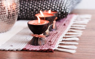 Konforlu ev dekorasyonu, hindistan cevizi kabuklu spa aromalı mumlar, çok renkli bir halı. 