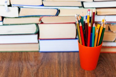 Plastik tutacakta renkli kalemler ve tahta masa üzerinde eski kitap yığını, eğitim konsepti arka planı, metin için metin alanı olan bir sürü kitap