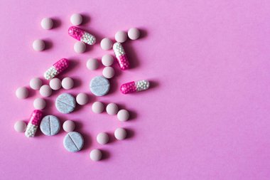 Renkli haplar, haplar, pembe arka planda kapsüller. Fotokopi alanı ile tedavi tedavisi için ilaç reçetesi