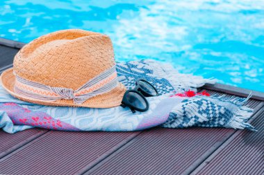 Eski yaz hasır hasır hasır hasır plaj şapkası, güneş gözlükleri ve yüzme havuzunun yanında örtünme giysisi, tropikal arka plan