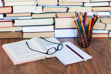 Ders kitabını, defteri, gözlükleri, kalemleri, tahta masanın üzerindeki eski kitap yığınını, eğitim konsepti geçmişini, metin için metin alanı olan bir sürü kitap yığınını aç