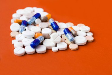 Bir sürü hap, tablet, kırmızı turuncu arka planda kapsüller. Fotokopi alanı ile tedavi tedavisi için ilaç reçetesi