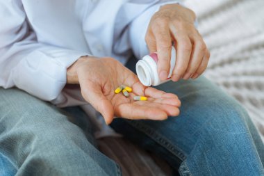 Kadın eli, elinde ilaç, elinde hapla yaşlı kadın elleri şişeden ilaç döküyor. 