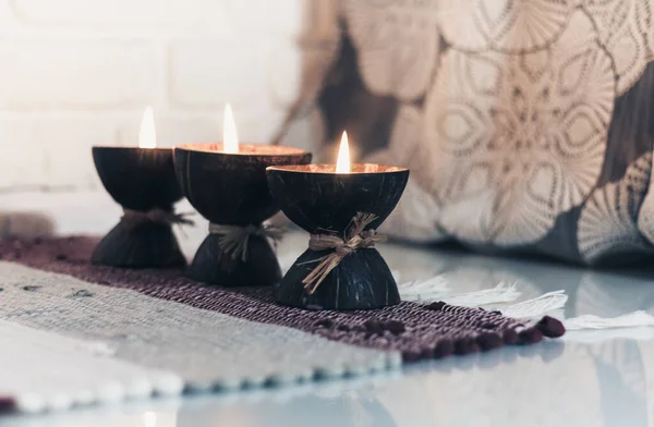 在白色的墙壁对面的毛织的彩色地毯和灰色的窗帘上 用椰子壳燃着温泉芬芳的蜡烛 温馨温馨的家 — 图库照片