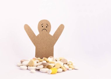 Renkli haplar ve beyaz arka planda bir mukavva adam figürü tabletler ve kapsüller. Fotokopi alanı ile tedavi tedavisi için ilaç reçetesi