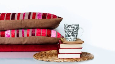 Konforlu ev dekorasyonu: bir fincan kahve, kitap yığını, yastıklar ve beyaz bir masanın üzerindeki ekose. Uzaktan eğitim. Karantina konsepti: