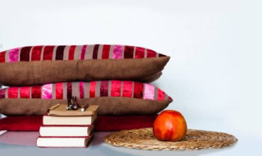 Konforlu ev dekorasyonu: Elma, kitap yığını, yastık ve ekose beyaz bir masa. Uzaktan eğitim. Karantina konsepti: