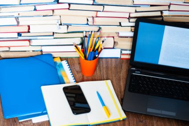 Ders kitabı, defter, dizüstü bilgisayar, cep telefonu akıllı telefon, yığınla kitap. Evde eğitim geçmişi, evde kalma kavramı