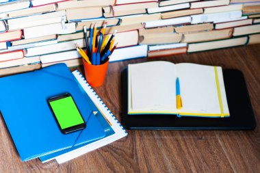 Ders kitabı, defter, yeşil ekran cep telefonu akıllı telefon ve yığınla kitap. Evden çalışmak, uzak eğitim geçmişi, evde kalma kavramı
