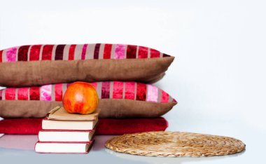 Konforlu ev dekorasyonu: Elma, kitap yığını, yastık ve ekose beyaz bir masa. Uzaktan eğitim. Karantina konsepti: