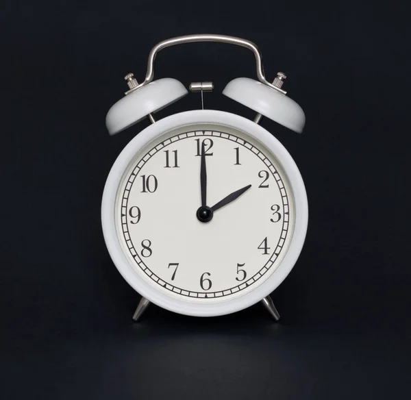 Old-style alarm clock, black and white, it\'s two o\'clock.