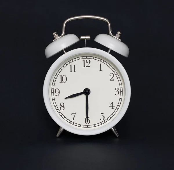 Old-style alarm clock, black and white, it\'s half past eight.