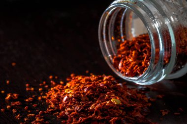 Koyu masanın üzerine dökülen kırmızı biber tanelerini yakın plan çek.