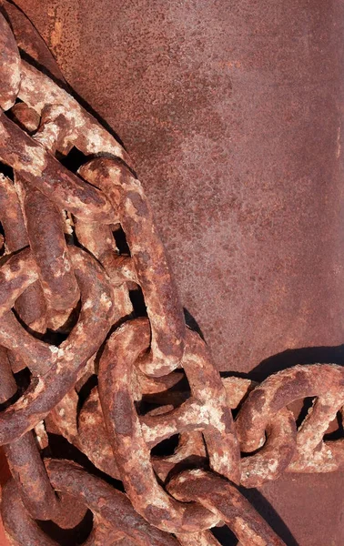 Large rusty and weathered industrial  chain links against a blank brown steel background