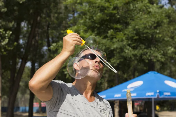 Yetişkin bir adam baloncuklar yapar