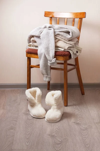 Sheepskin slippers, stack of warm clothes — Stock Photo, Image