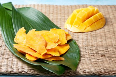 Kurutulmuş mango parçaları, saman arkaplanda taze mango. Yukarıdan görünüm