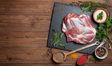 Ahşap bir arka planda otlu ve baharatlı kuzu budu. Yukarıdan görünüm