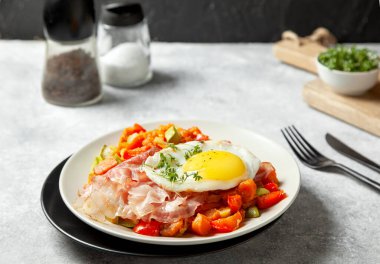 Patates, biber, kabak, beyaz tabakta gri beton arka planda kızarmış yumurta ile haşlanmış kahvaltı..