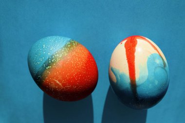 Paskalya için canlı renkli yumurtalar kırmızı ve mavi kağıtların üzerinde duruyor.