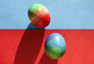 Paskalya için canlı renkli yumurtalar kırmızı ve mavi kağıtların üzerinde duruyor.