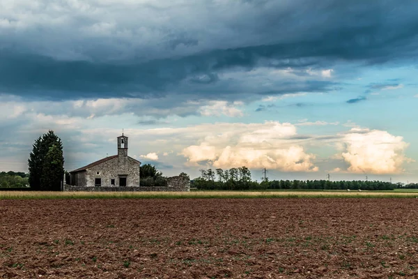 Tormenta llegando a una pequeña iglesia en los campos —  Fotos de Stock