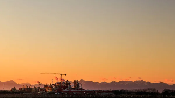 Solen går ner bakom en industri — Stockfoto