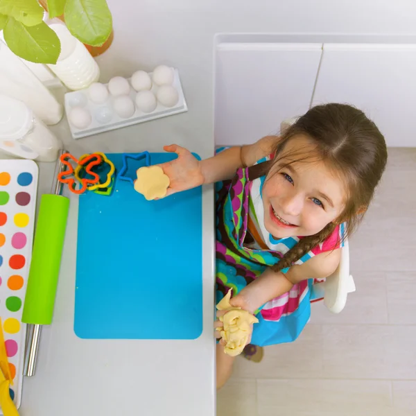 Little girl preparing the dough for a cookie on kitchen — Stock Photo, Image