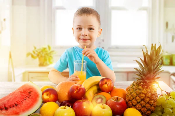 Little boy drinks fresh juice with fruits in kitchen — Stock Photo, Image