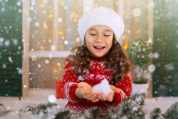 Fille enfant heureux étend sa main pour attraper des flocons de neige tombant . — Photo