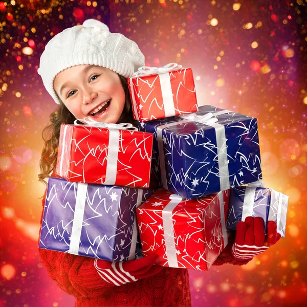 Glückliches kleines Mädchen mit Weihnachtsgeschenken auf Lichtern Hintergrund — Stockfoto