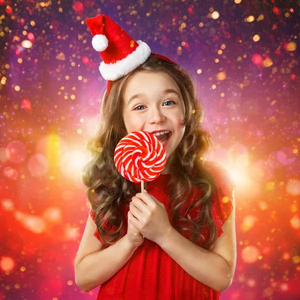 Κοριτσάκι σε το καπέλο santa με καραμέλα από ζαχαροκάλαμο. Χριστούγεννα του χρόνου — Φωτογραφία Αρχείου